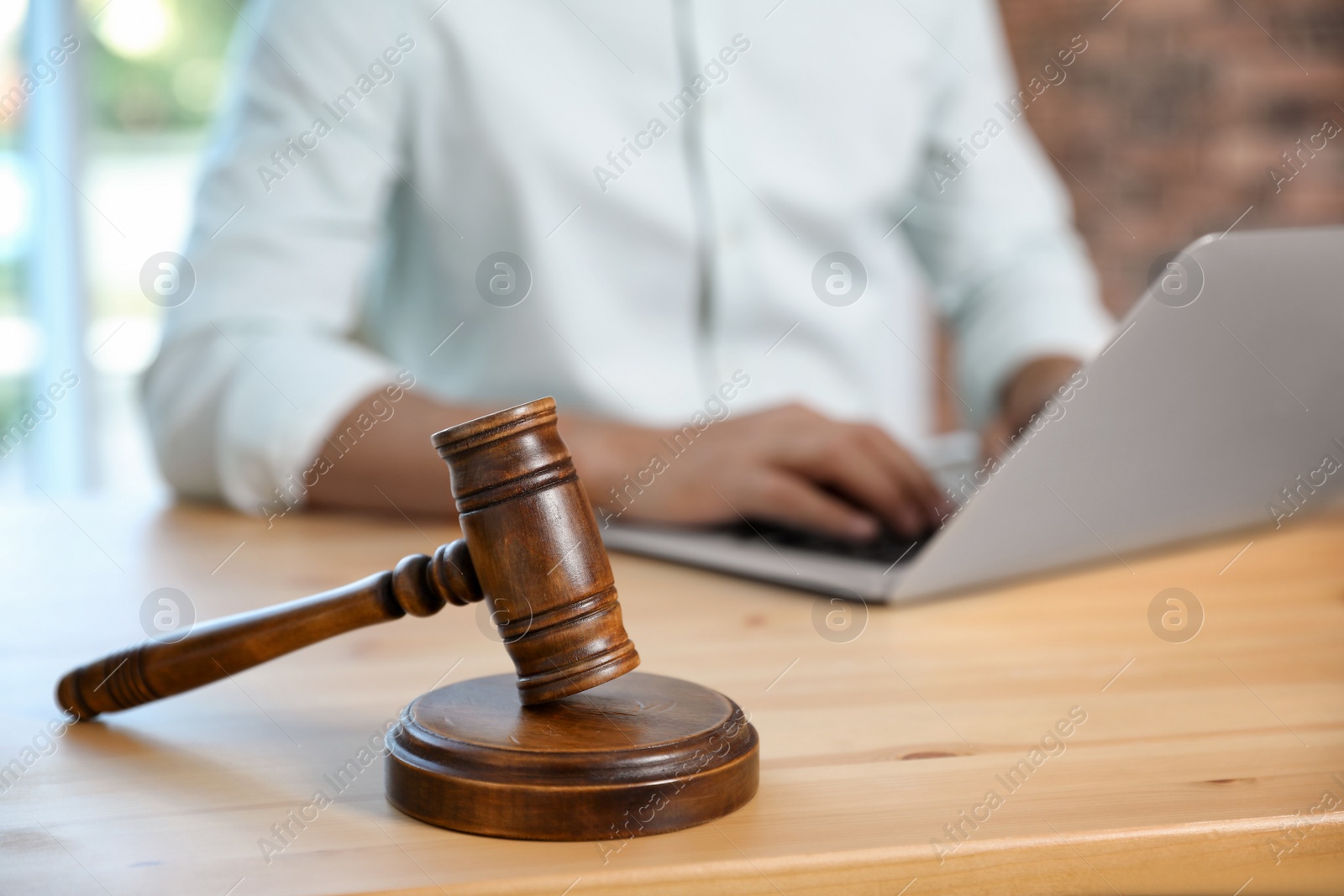 Photo of Wooden gavel and blurred notary with laptop on background