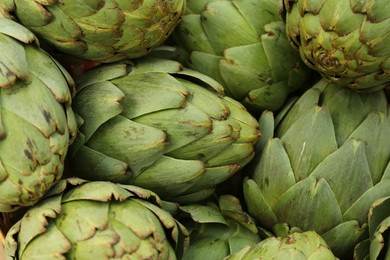 Photo of Many fresh raw artichokes as background, top view