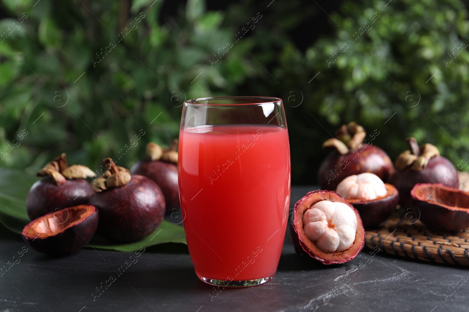 Photo of Delicious mangosteen juice in glass on dark table