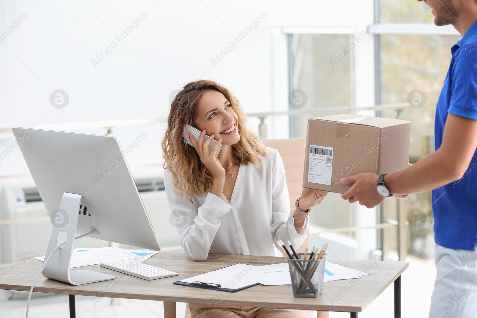 Photo of Young busy woman receiving parcel from courier in office