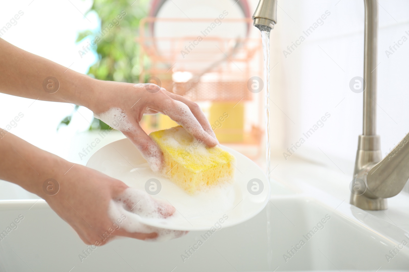 Photo of Woman washing ceramic plate in kitchen, closeup