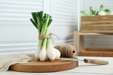 Photo of Bunch of green spring onions on white wooden table