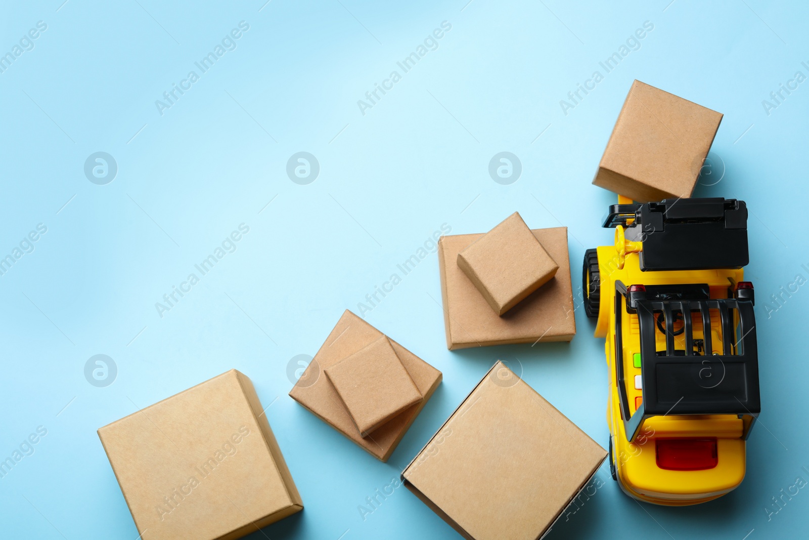 Photo of Top view of toy forklift with boxes on blue background, space for text. Logistics and wholesale concept