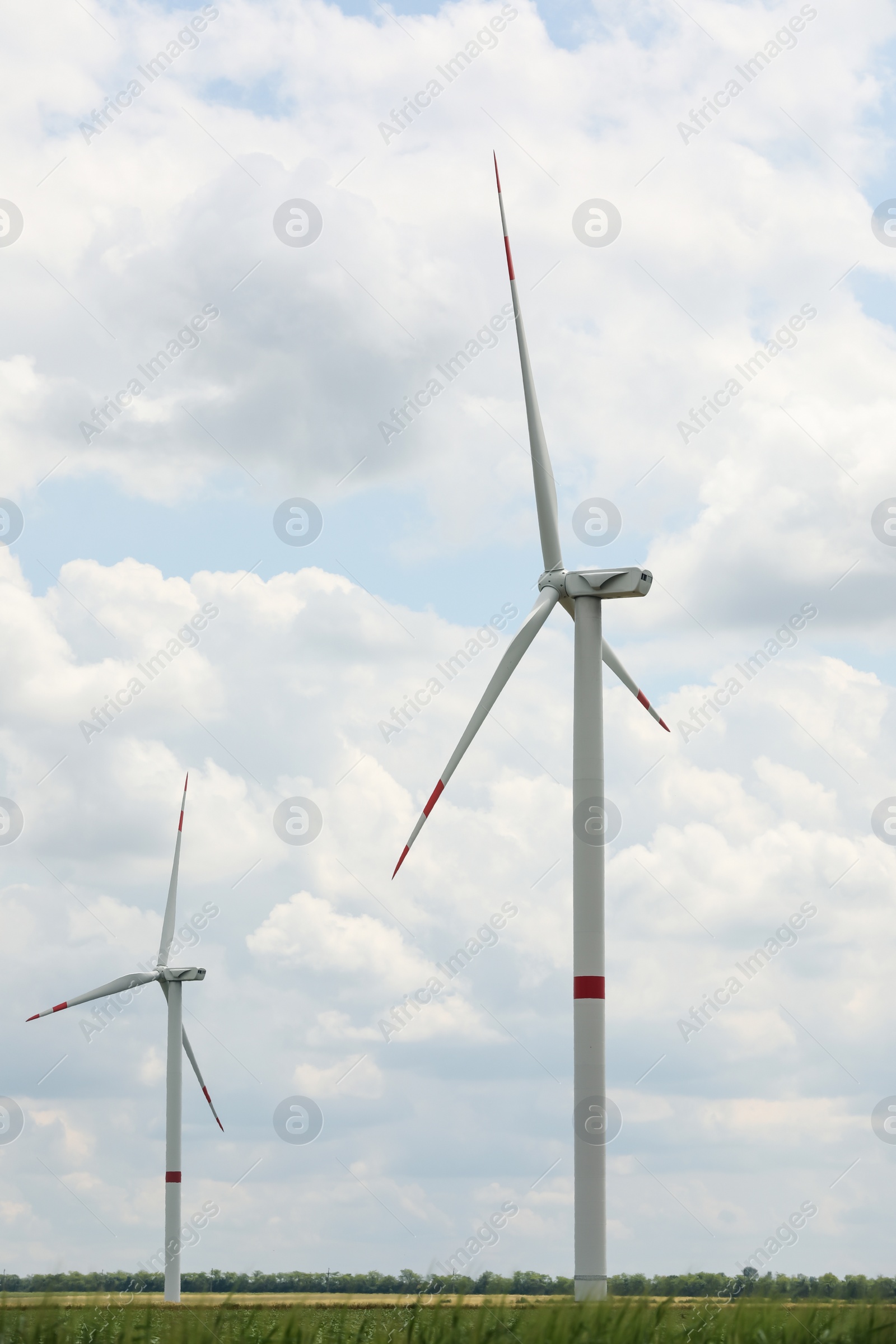 Photo of Modern wind turbines in field on cloudy day. Alternative energy source