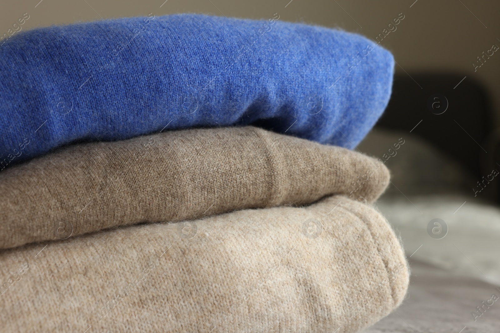 Photo of Folded color sweaters on light background, closeup