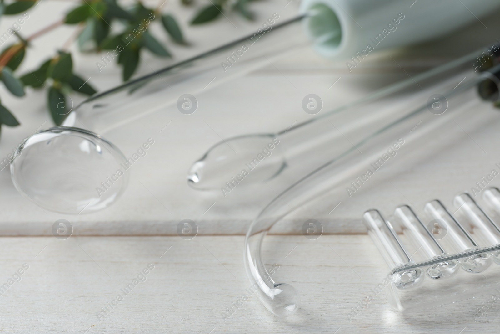 Photo of Darsonval with different nozzles on white wooden table, closeup