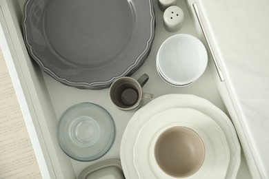 Photo of Open drawer of kitchen cabinet with different dishware, top view