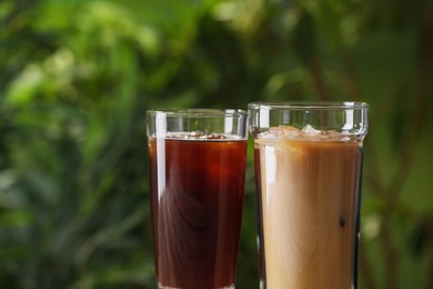 Photo of Glasses of fresh iced coffee outdoors, closeup. Space for text