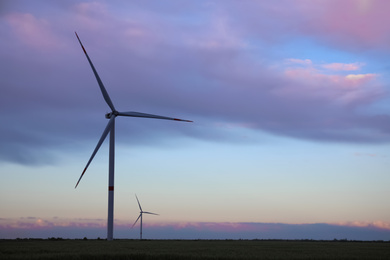 Photo of Beautiful view of field with wind turbines in evening. Alternative energy source