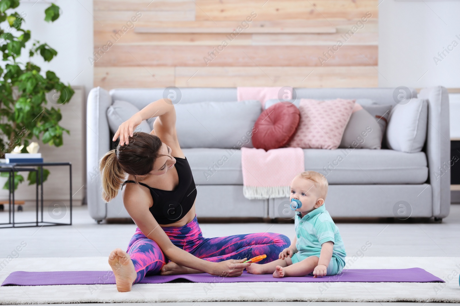 Photo of Young sportive woman doing exercise with her son at home. Fitness training