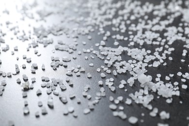 Scattered white natural salt on black table, closeup