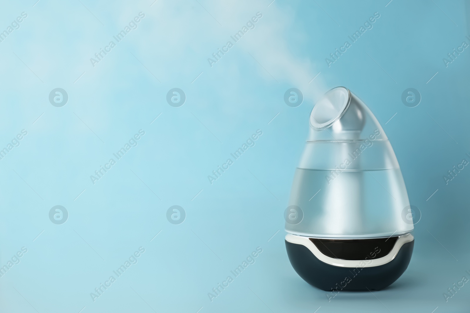 Photo of Modern air humidifier on light blue background. Space for text