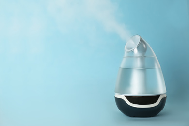 Modern air humidifier on light blue background. Space for text