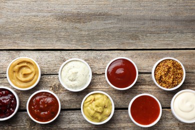 Photo of Different tasty sauces in bowls on wooden table, flat lay. Space for text