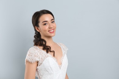 Photo of Young bride with beautiful wedding hairstyle on light grey background. Space for text