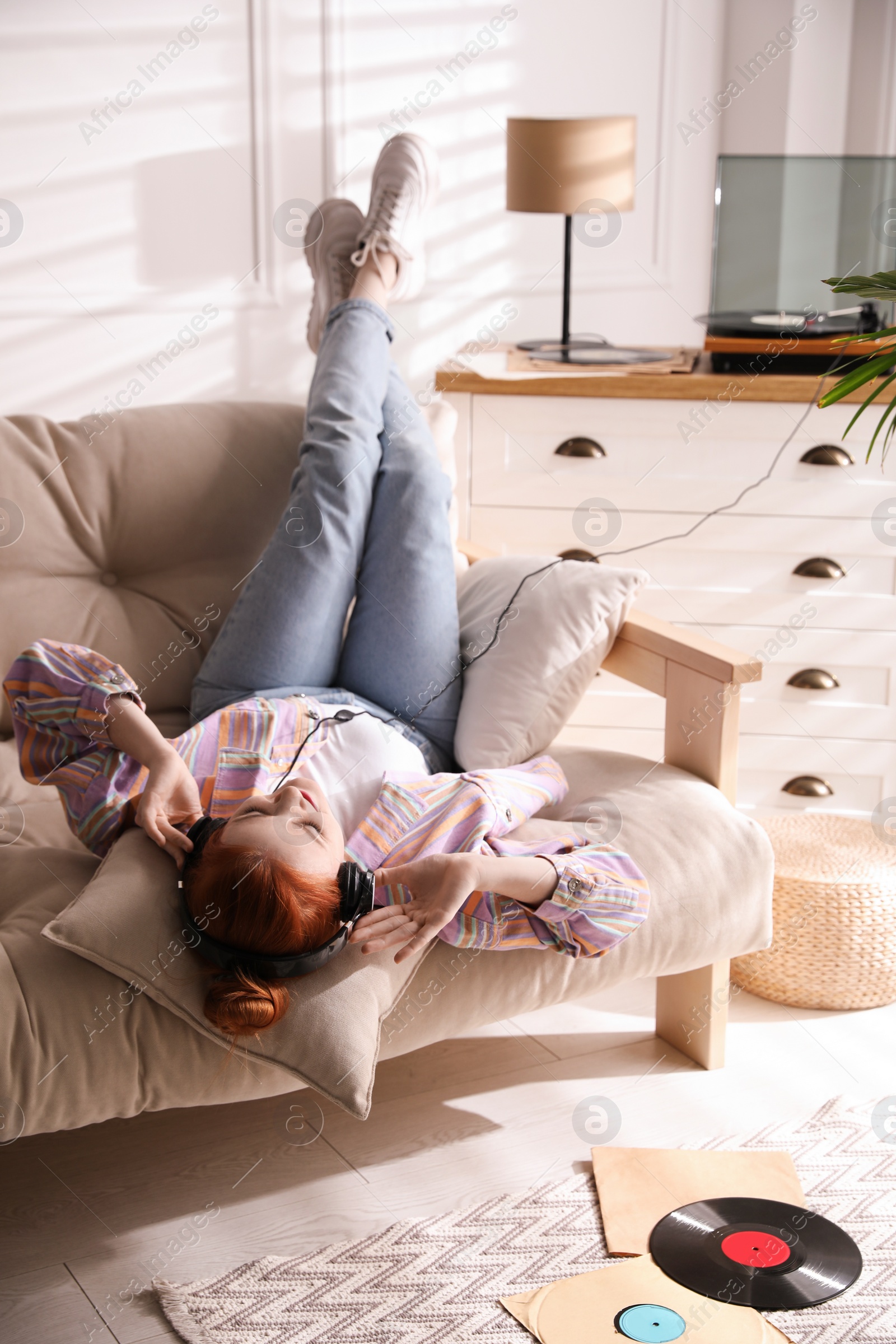 Photo of Young woman listening to music with turntable in living room