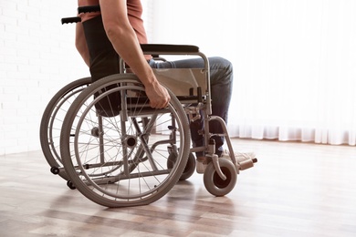 Photo of Man sitting in wheelchair near window at home, closeup