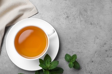 Photo of Cup of hot aromatic mint tea on light grey table, flat lay. Space for text