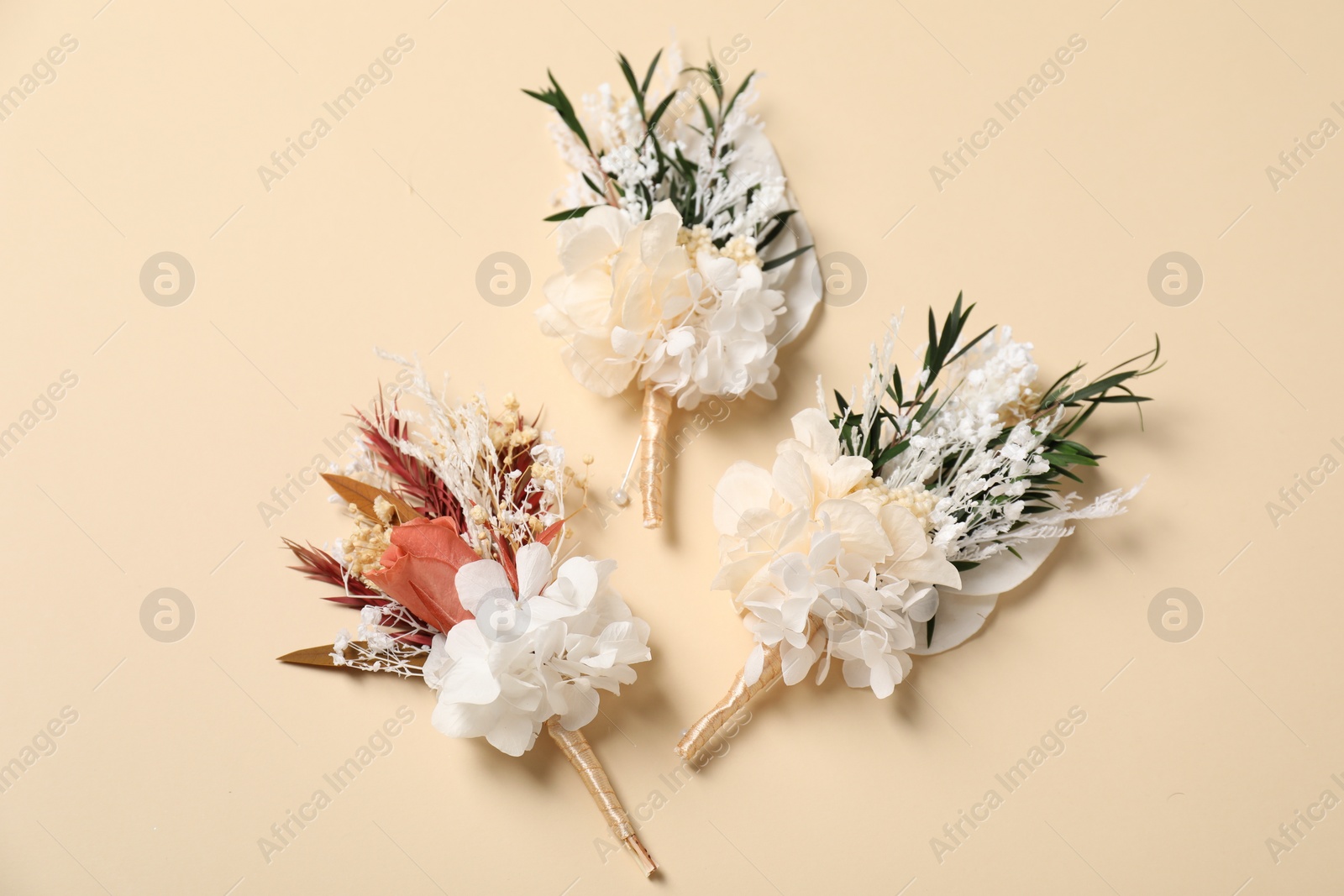 Photo of Stylish boutonnieres on beige background, flat lay