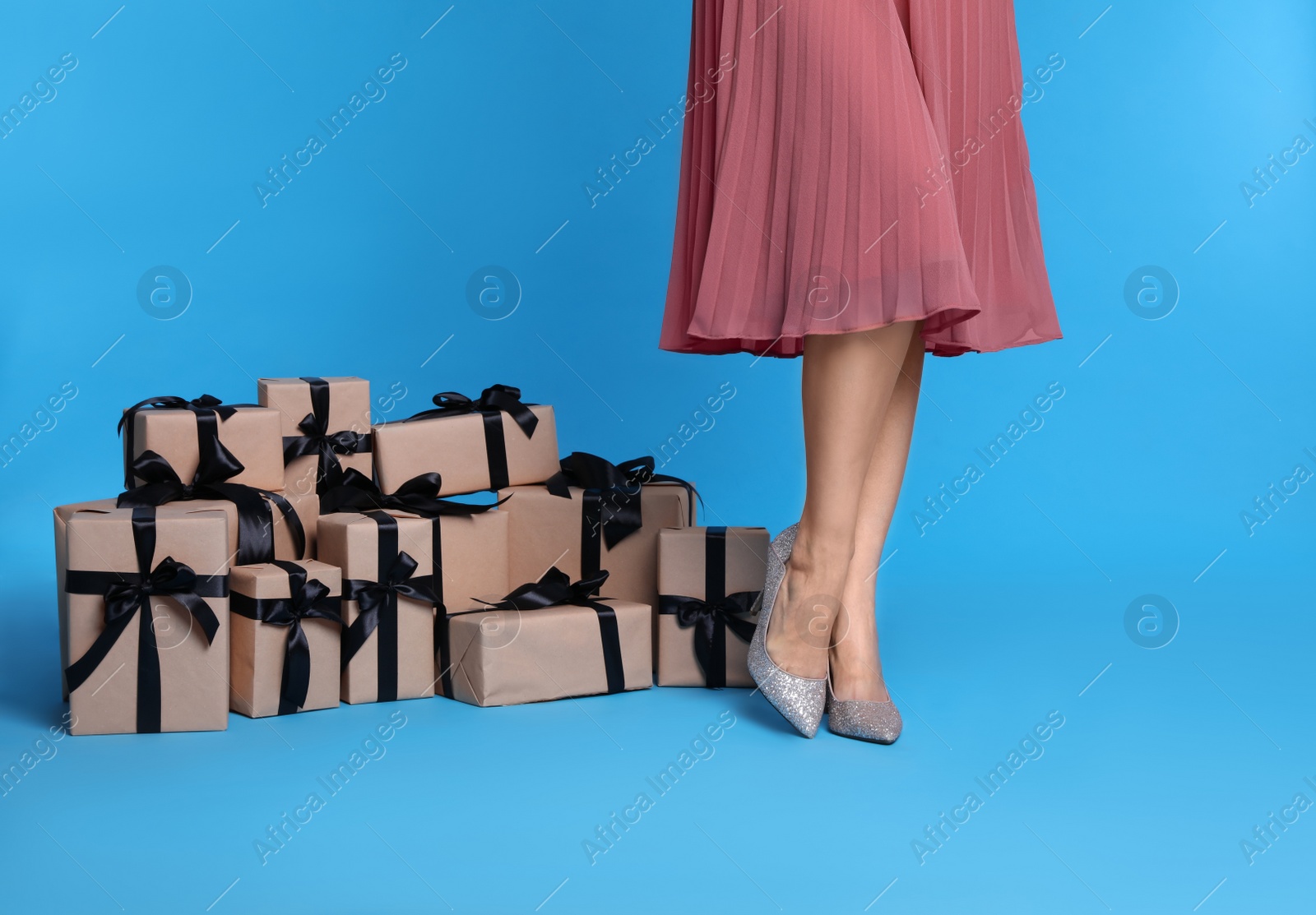 Photo of Woman and gift boxes on light blue background, closeup. Black Friday