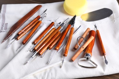 Photo of Set of different clay crafting tools on wooden table, closeup