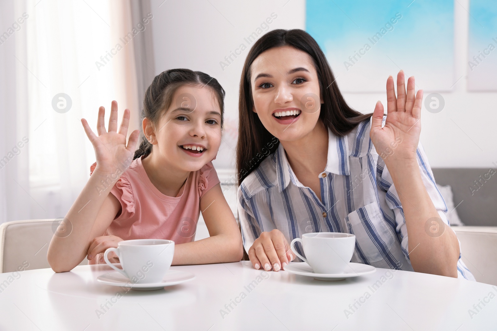 Photo of Mother and daughter using video chat at table indoors, view from camera perspective