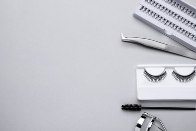 Flat lay composition with fake eyelashes, brush and tools on light grey background. Space for text