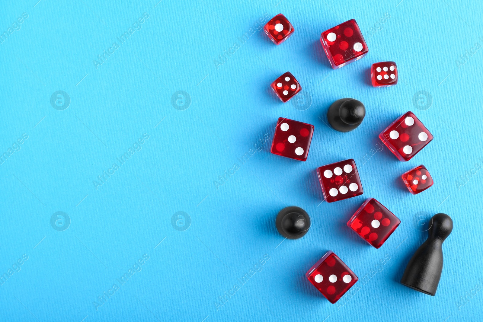 Photo of Many red dices and color game pieces on light blue background, flat lay. Space for text