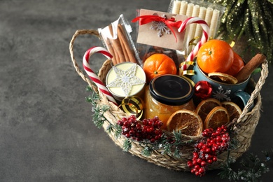 Wicker basket with gift set and Christmas decor on grey table. Space for text