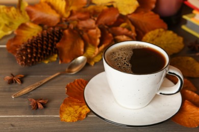 Photo of Composition with cup of hot coffee and autumn leaves on wooden table. Space for text