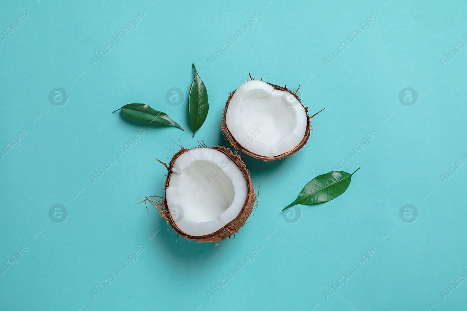 Photo of Coconut halves with leaves on color background