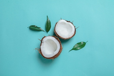 Coconut halves with leaves on color background