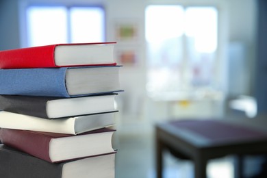 Image of Many stacked hardcover books in office, space for text