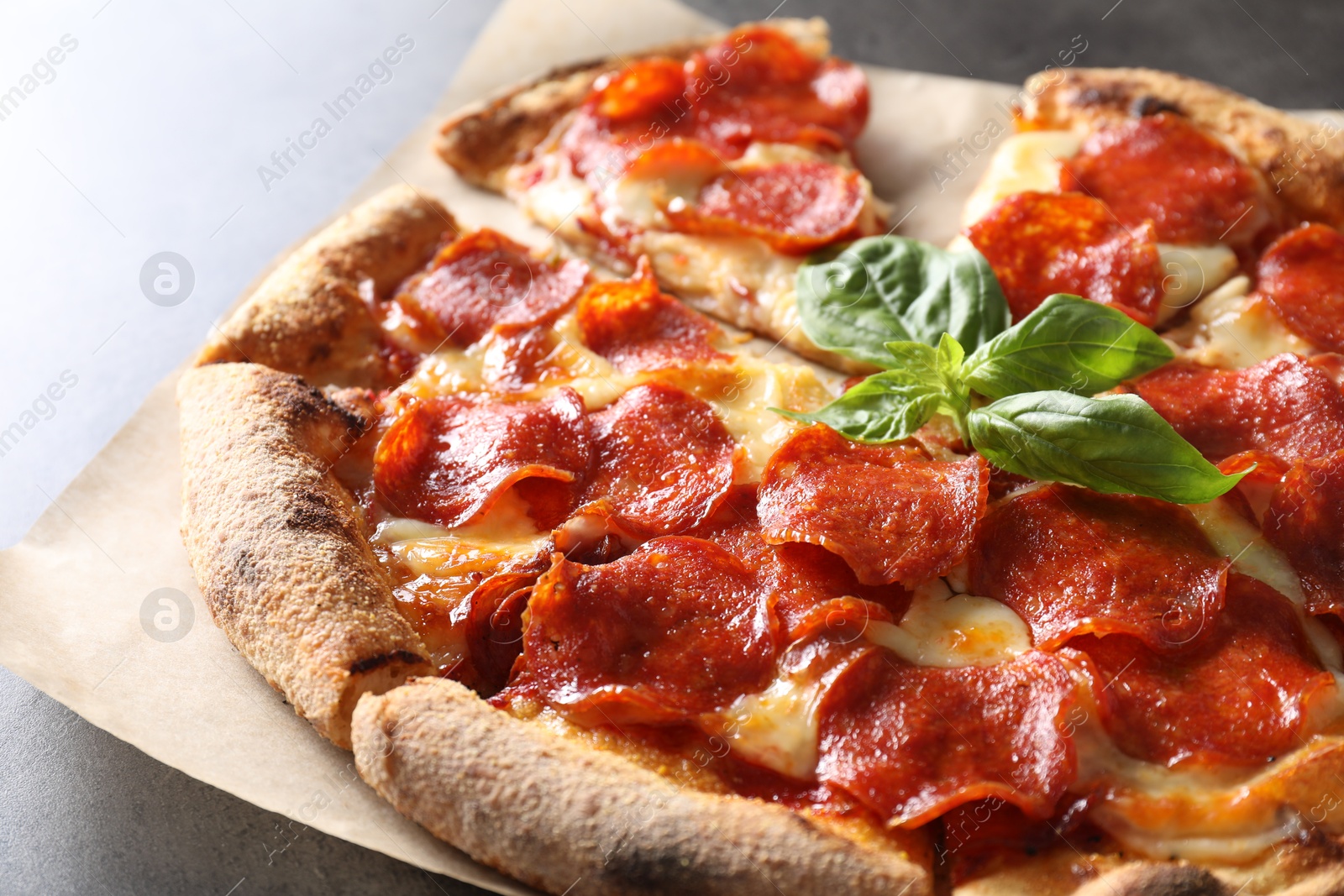 Photo of Tasty pepperoni pizza with basil on grey table, closeup