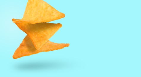 Tasty tortilla chips falling on cyan background, space for text