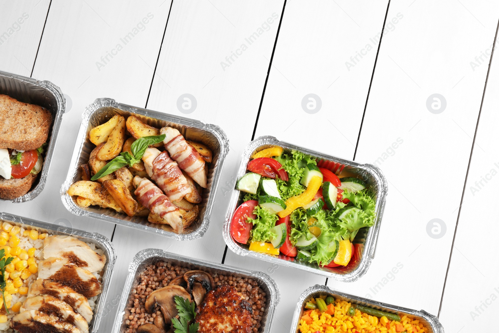 Photo of Lunchboxes on white wooden table, flat lay. Healthy food delivery