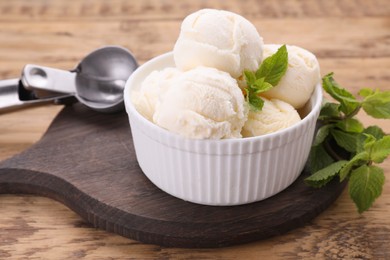 Bowl of ice cream and mint leaves on wooden table