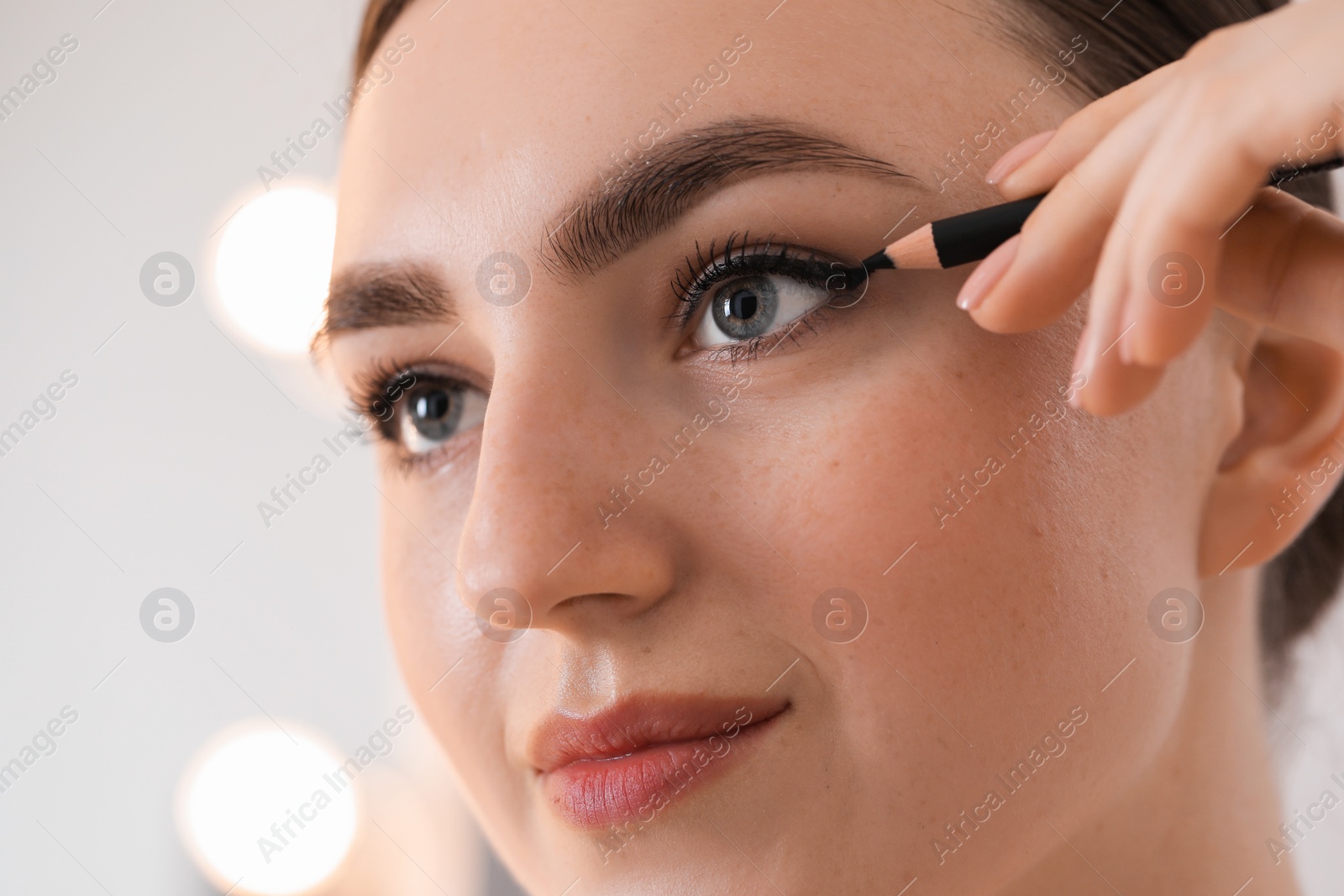 Photo of Makeup product. Woman applying black eyeliner indoors, closeup