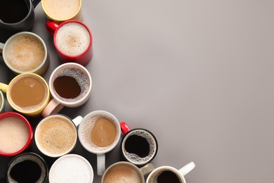 Photo of Many different cups with aromatic coffee on grey table, flat lay. Space for text