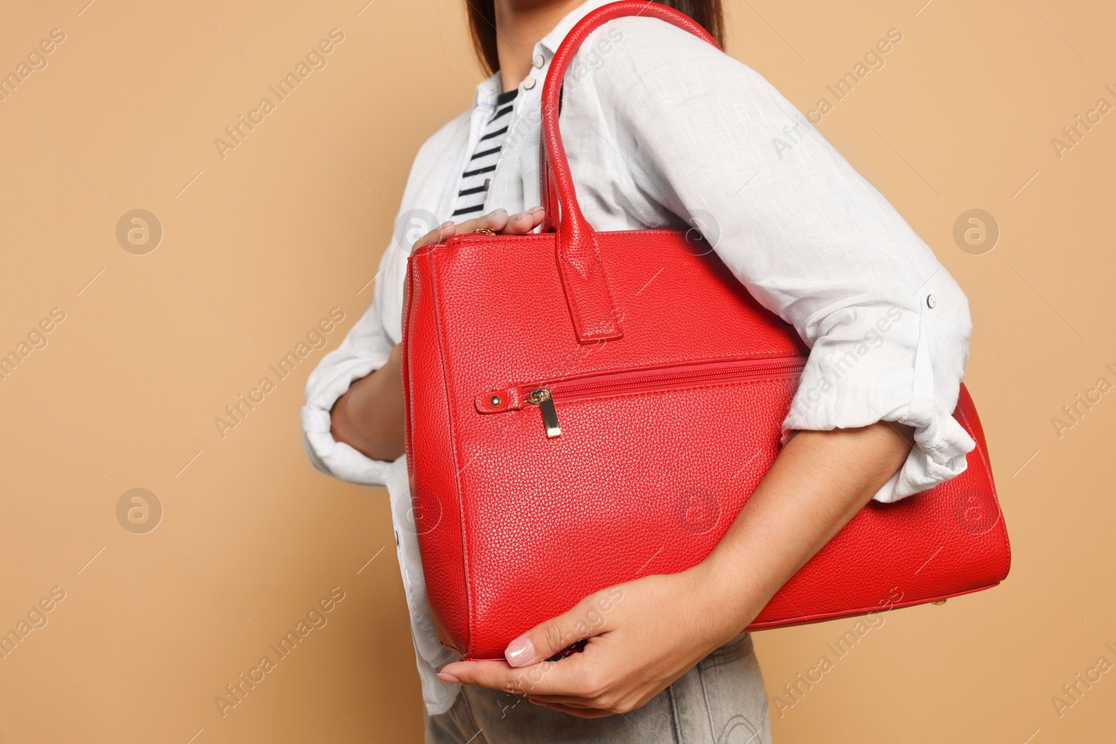 Photo of Young woman with stylish bag on beige background, closeup