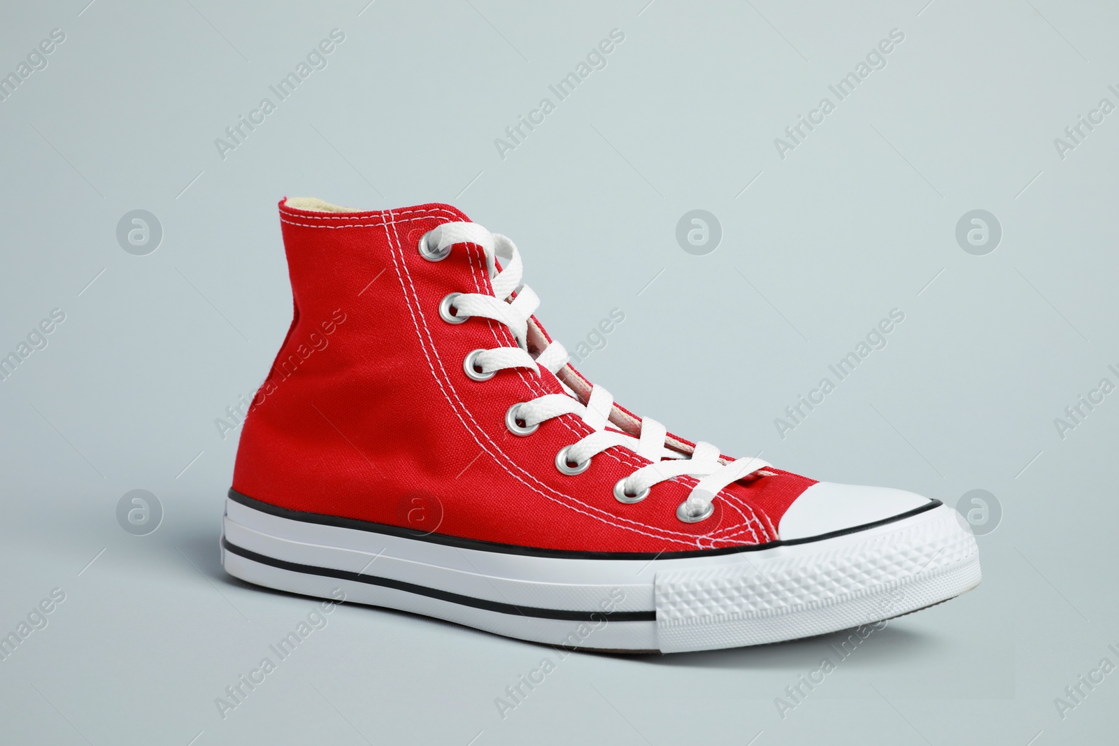 Photo of One new stylish red sneaker on light grey background