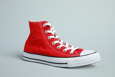 One new stylish red sneaker on light grey background