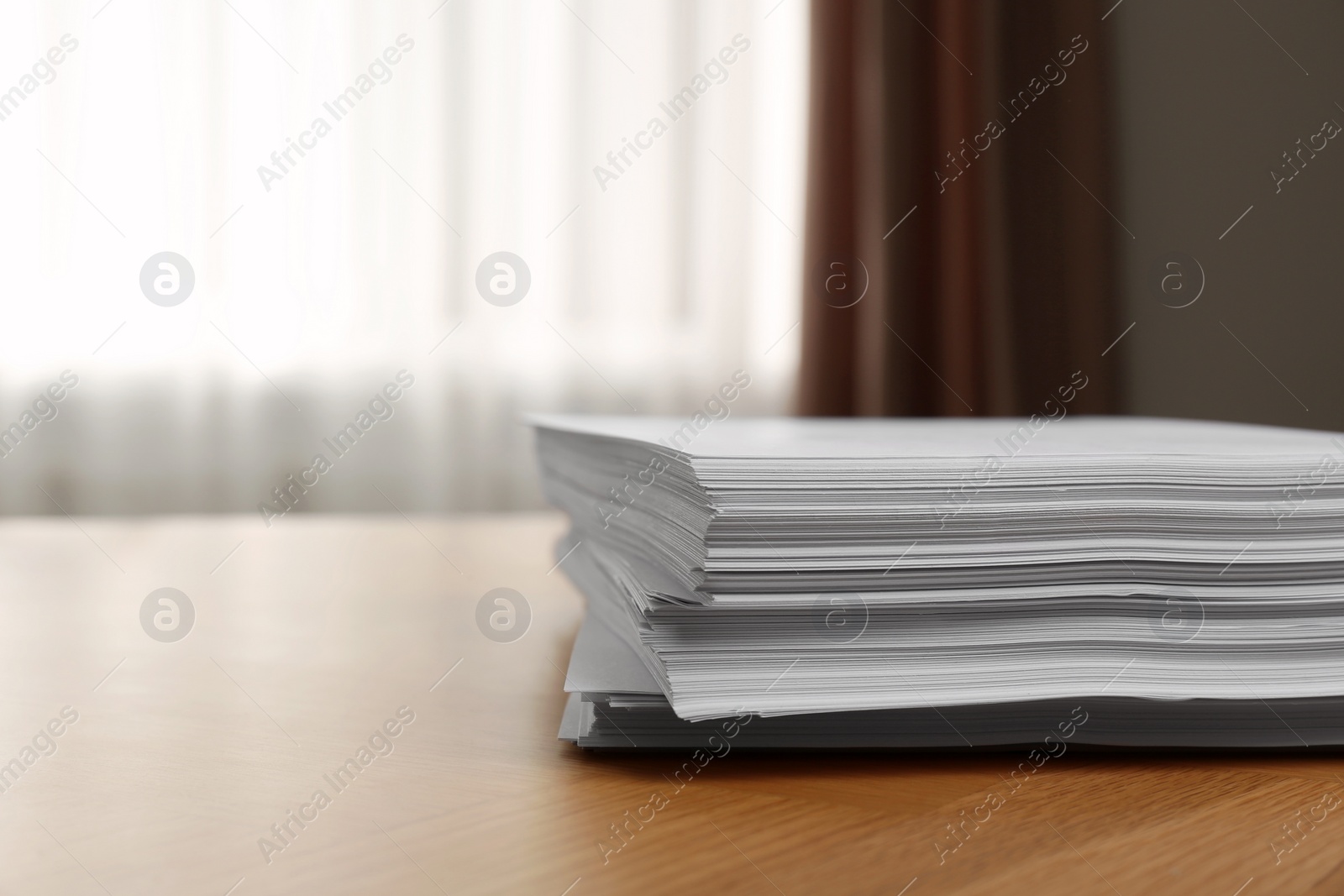 Photo of Stack of paper sheets on wooden table indoors. Space for text