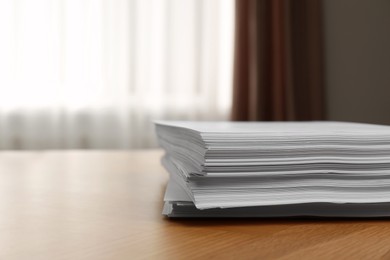 Stack of paper sheets on wooden table indoors. Space for text