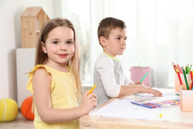 Photo of Little children drawing at table indoors. Learning and playing