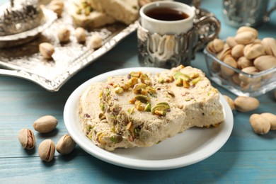 Photo of Tasty halva with pistachios served on light blue wooden table, closeup