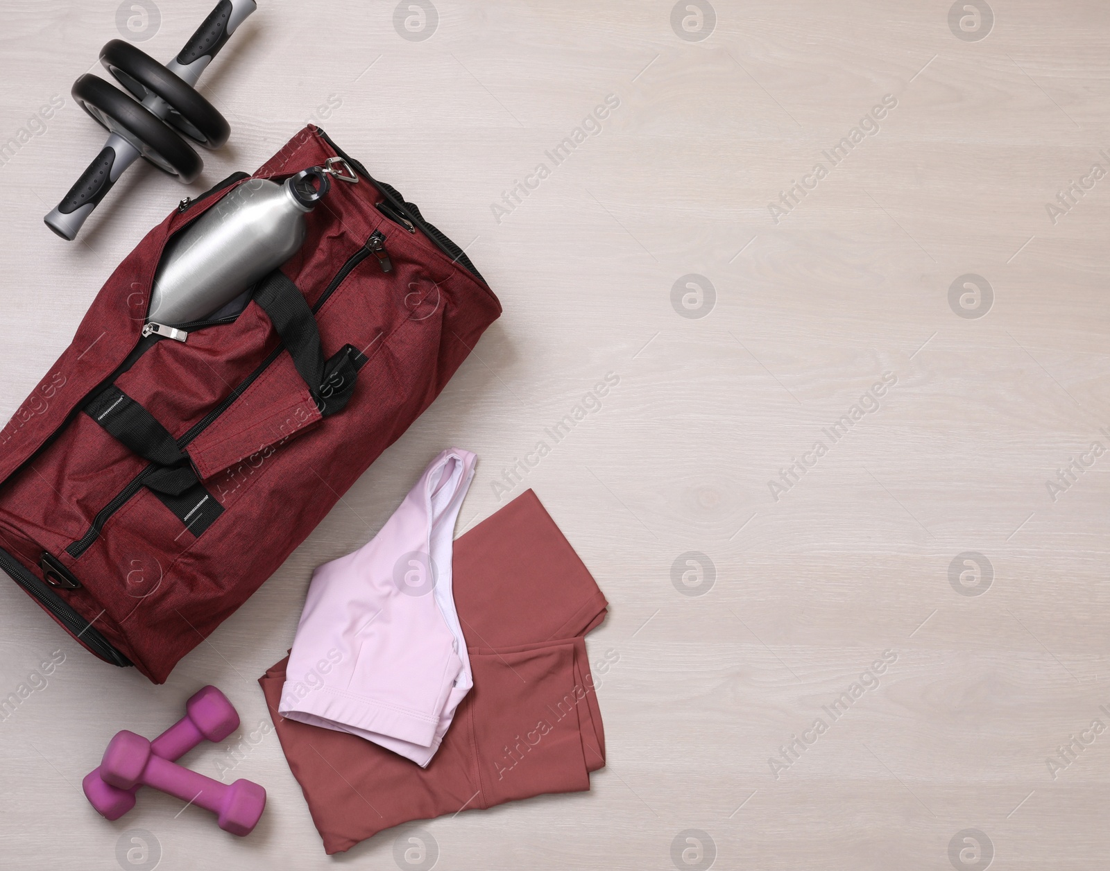 Photo of Gym bag and sports equipment on wooden background, flat lay. Space for text