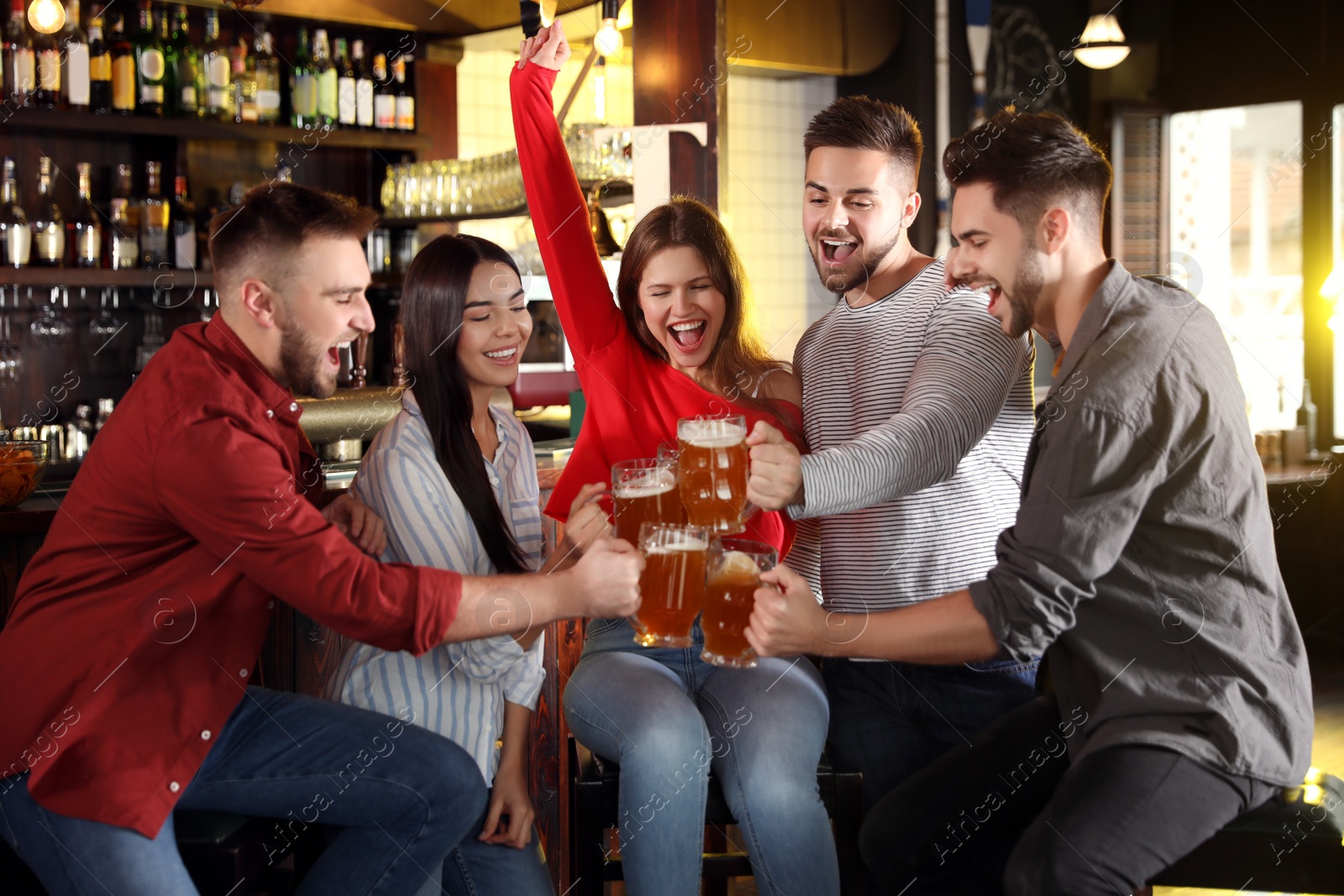 Photo of Group of friends celebrating victory of favorite football team in sport bar