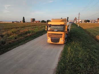 Modern yellow truck on country road. Space for text