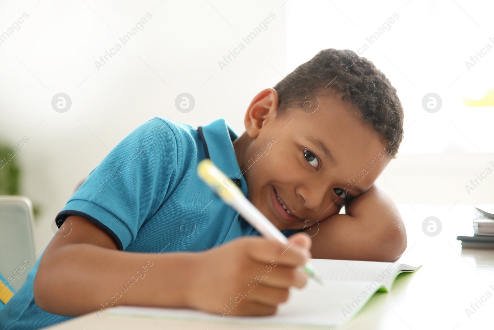 Photo of Cute little child doing assignment at desk in classroom. Elementary school